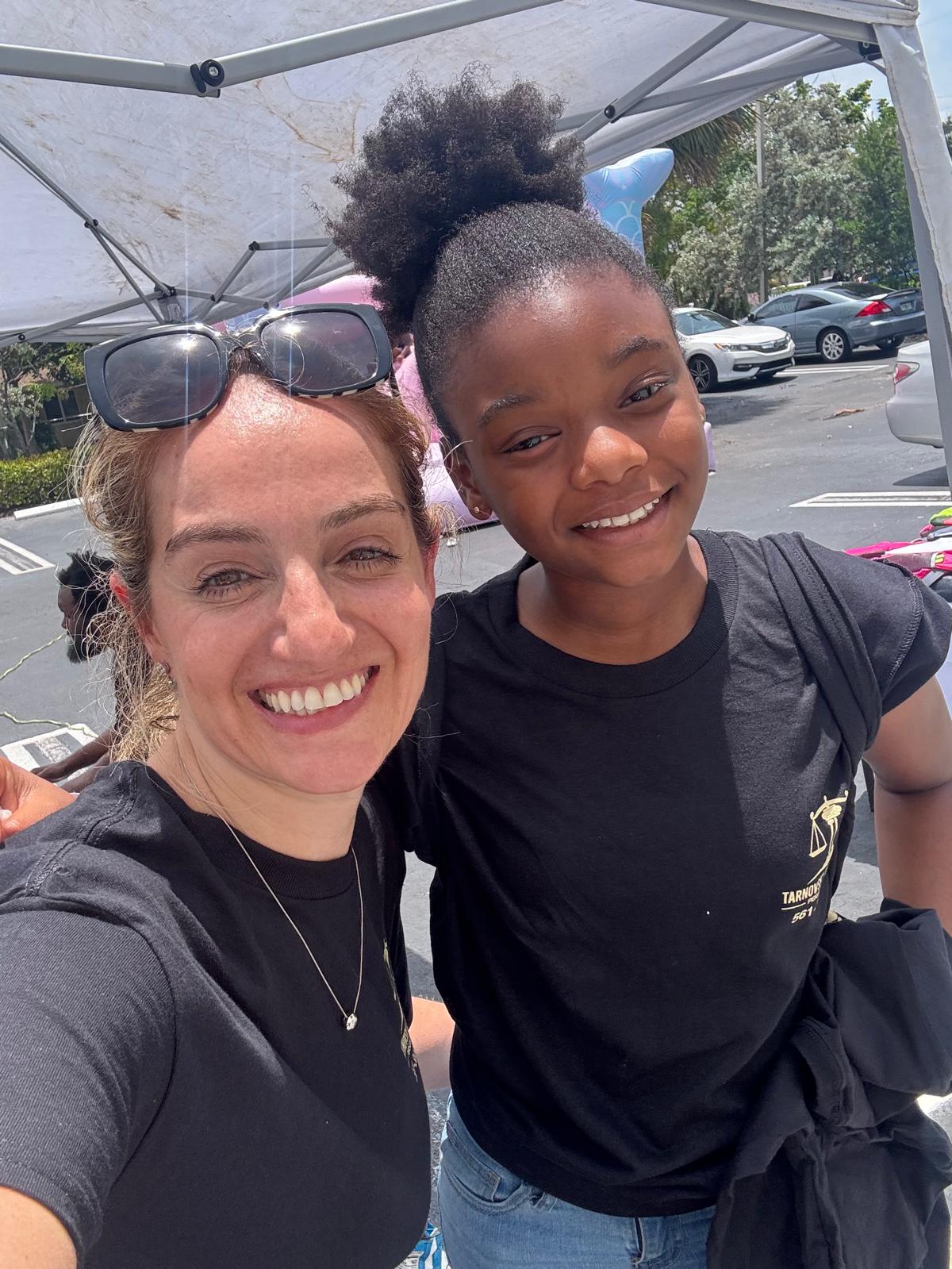 Attorney Irina Tarnovsky smiling with a young attendee at a Broward County back-to-school community event